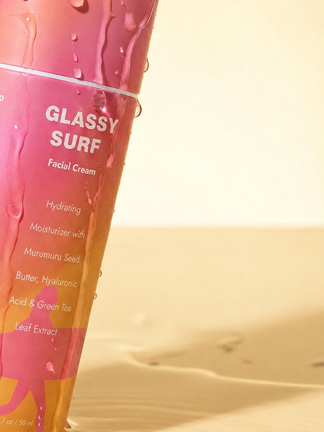 Close-up of Glassy Surf Hydrating Facial Cream covered in water droplets with the white bottle seam above the product name