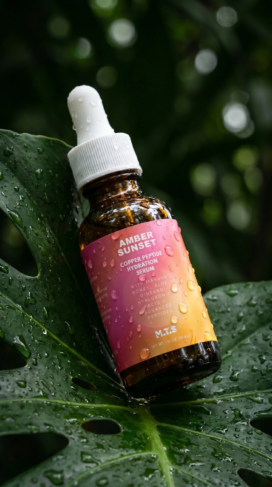 Amber Sunset serum bottle nestled in dew covered tropical leaves