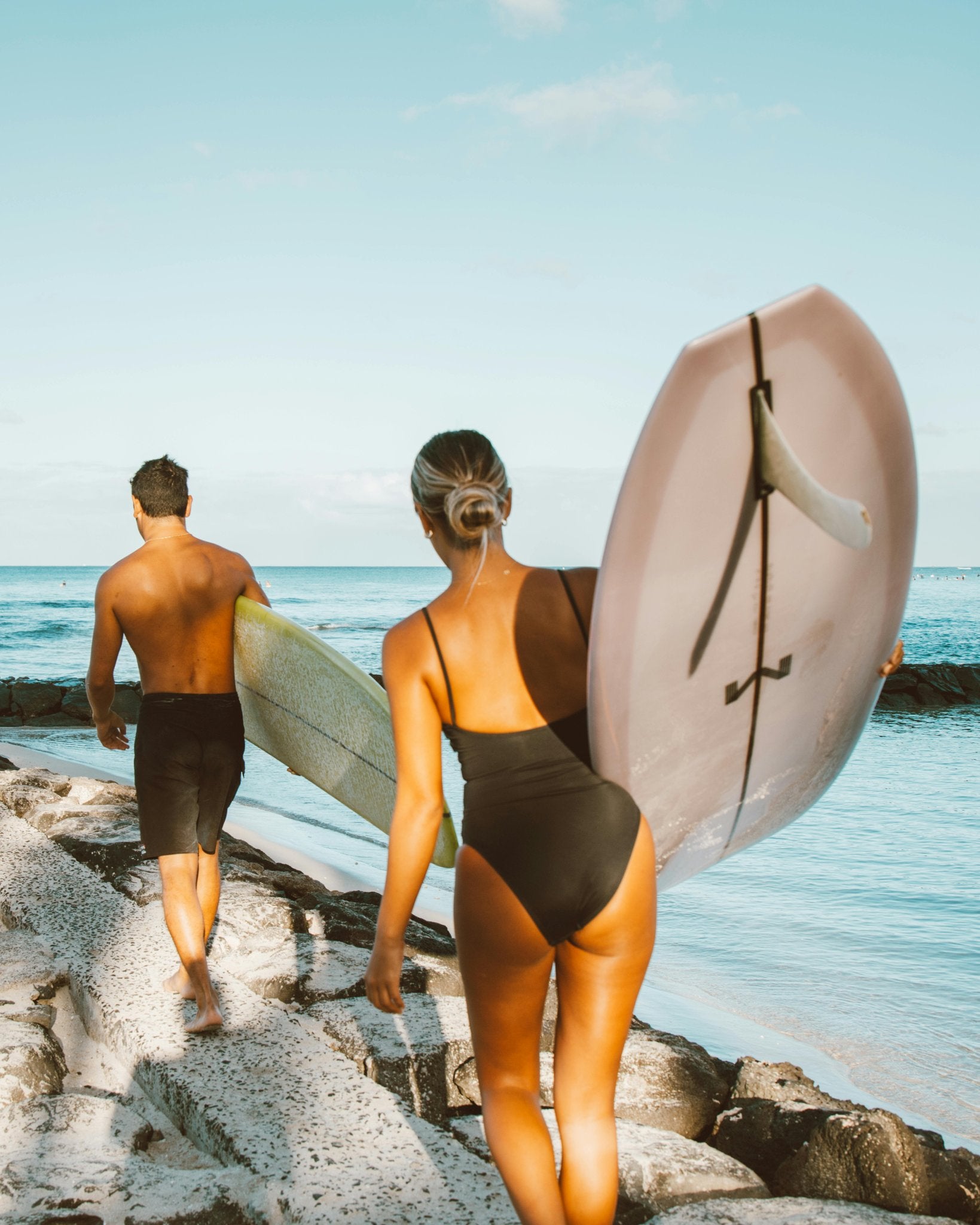 Two surfers walking into bright blue ocean water